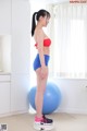 A woman in a red top and blue shorts standing on a blue ball.