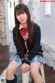 A young woman in a school uniform sitting on a chair.